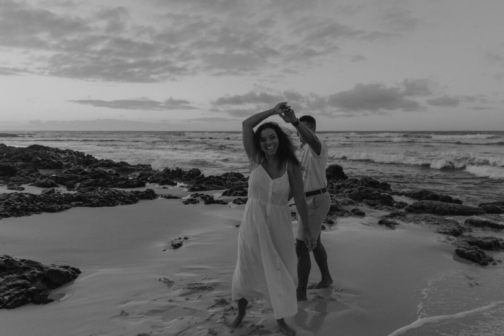 Black and white of couple dancing between lava rock at Oahu Hawaii beach