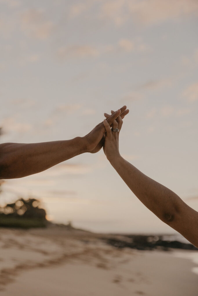 Couple holding hands at sunrise in Oahu Beach