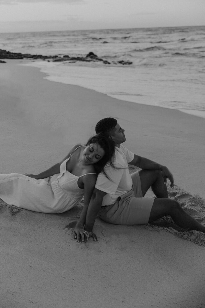 couple sitting in the sand at sunrise on Oahu Hawaii Beach