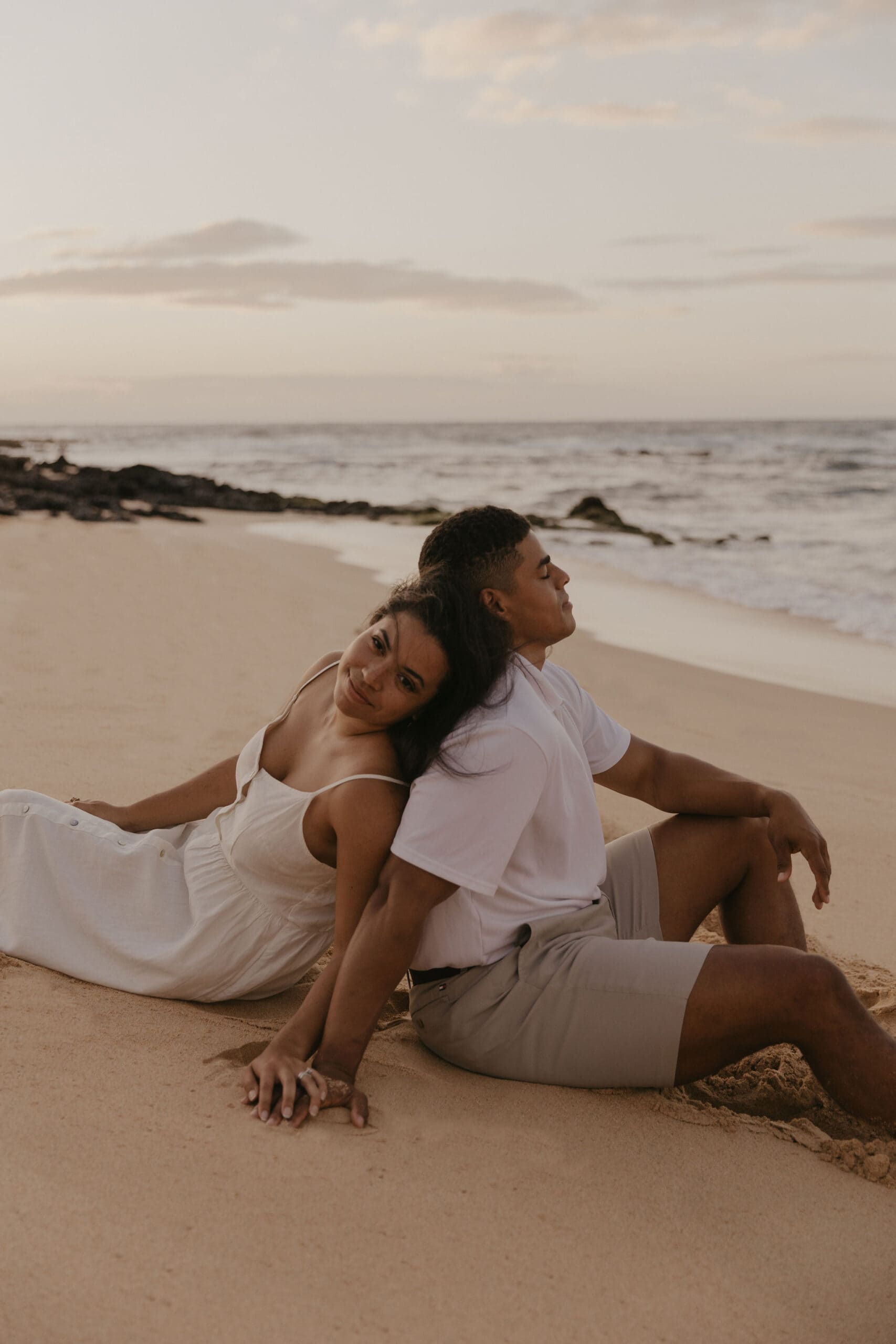 couple sitting in the sand at sunrise on Oahu Hawaii Beach