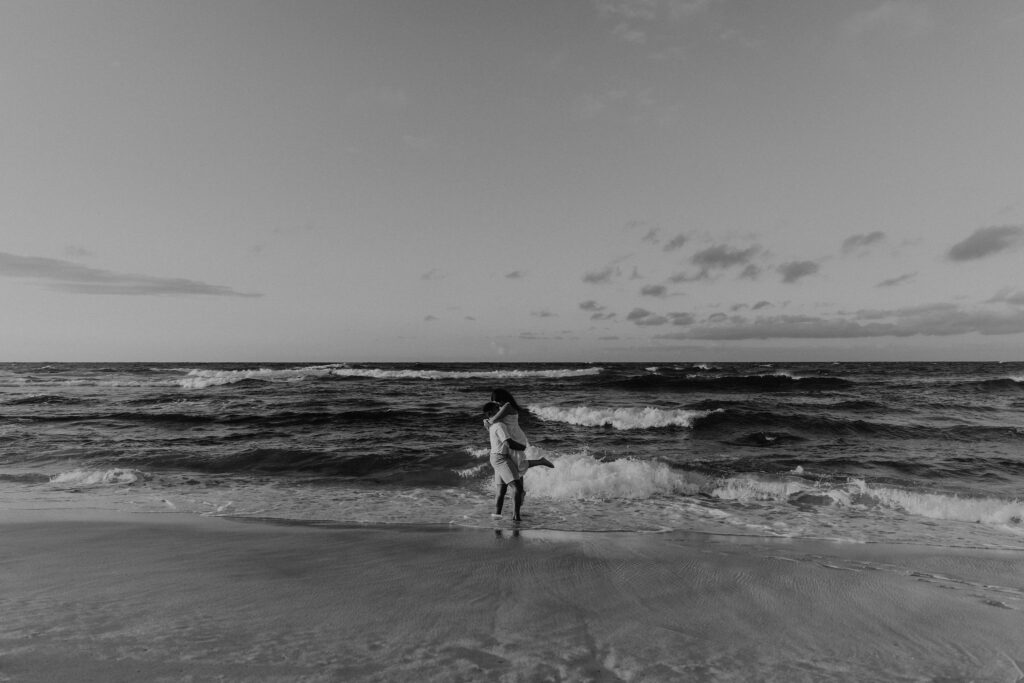 Black and white of couple kissing on the beach at sunrise in Oahu, Hawaii