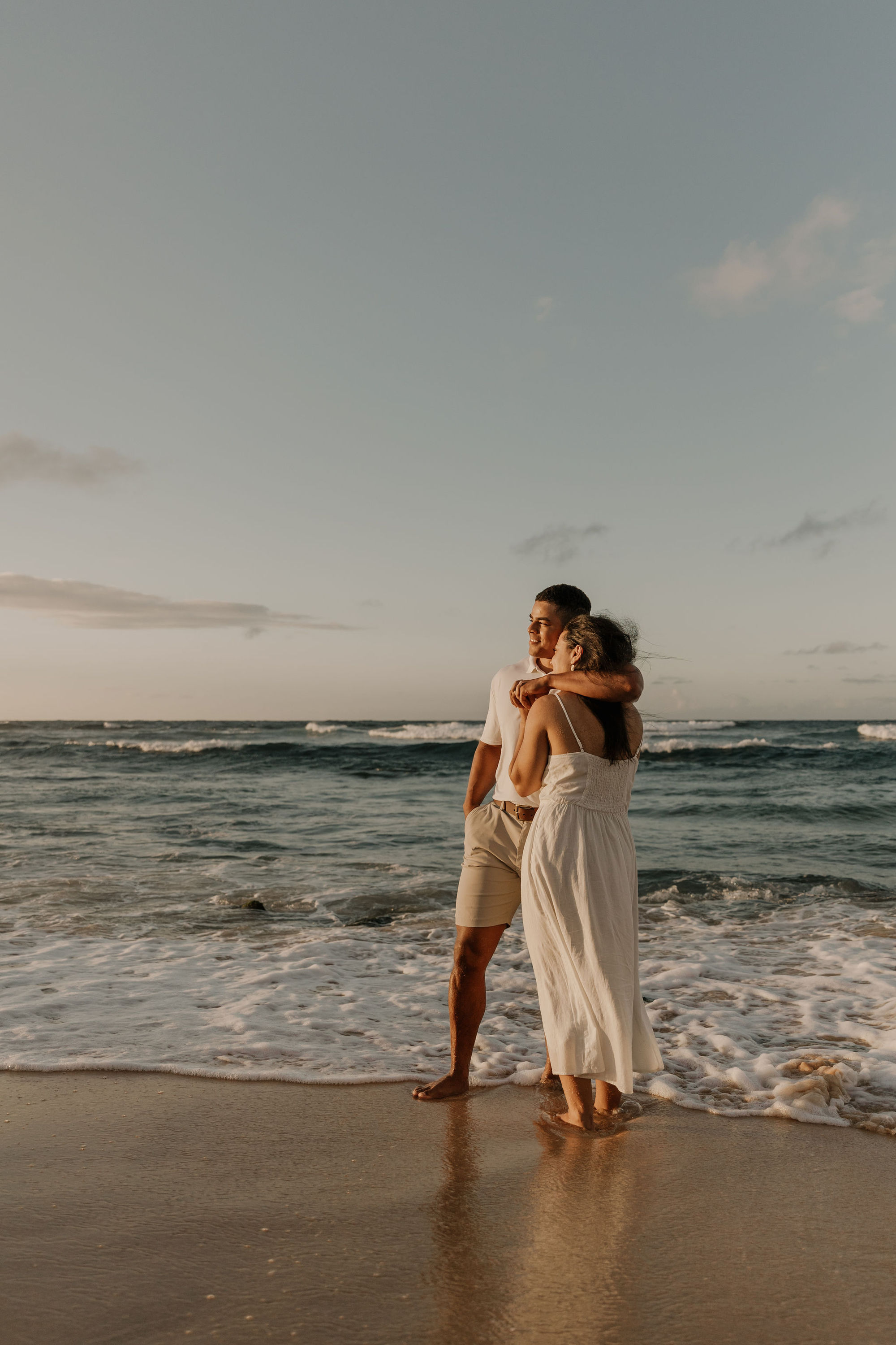 Couple watching the sunrise on the beach in Oahu, Hawaii