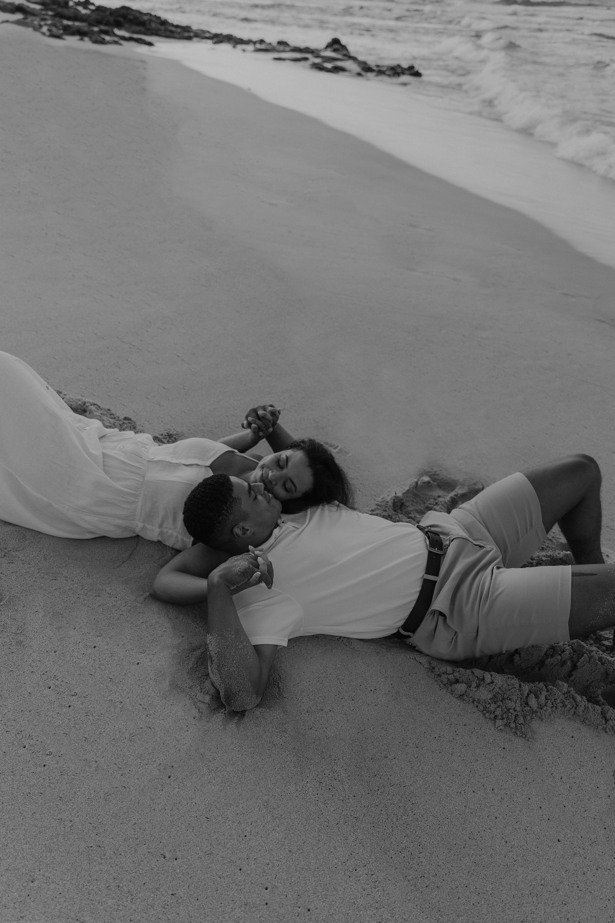 Couple kissing in the sand of a beach in Oahu, Hawaii