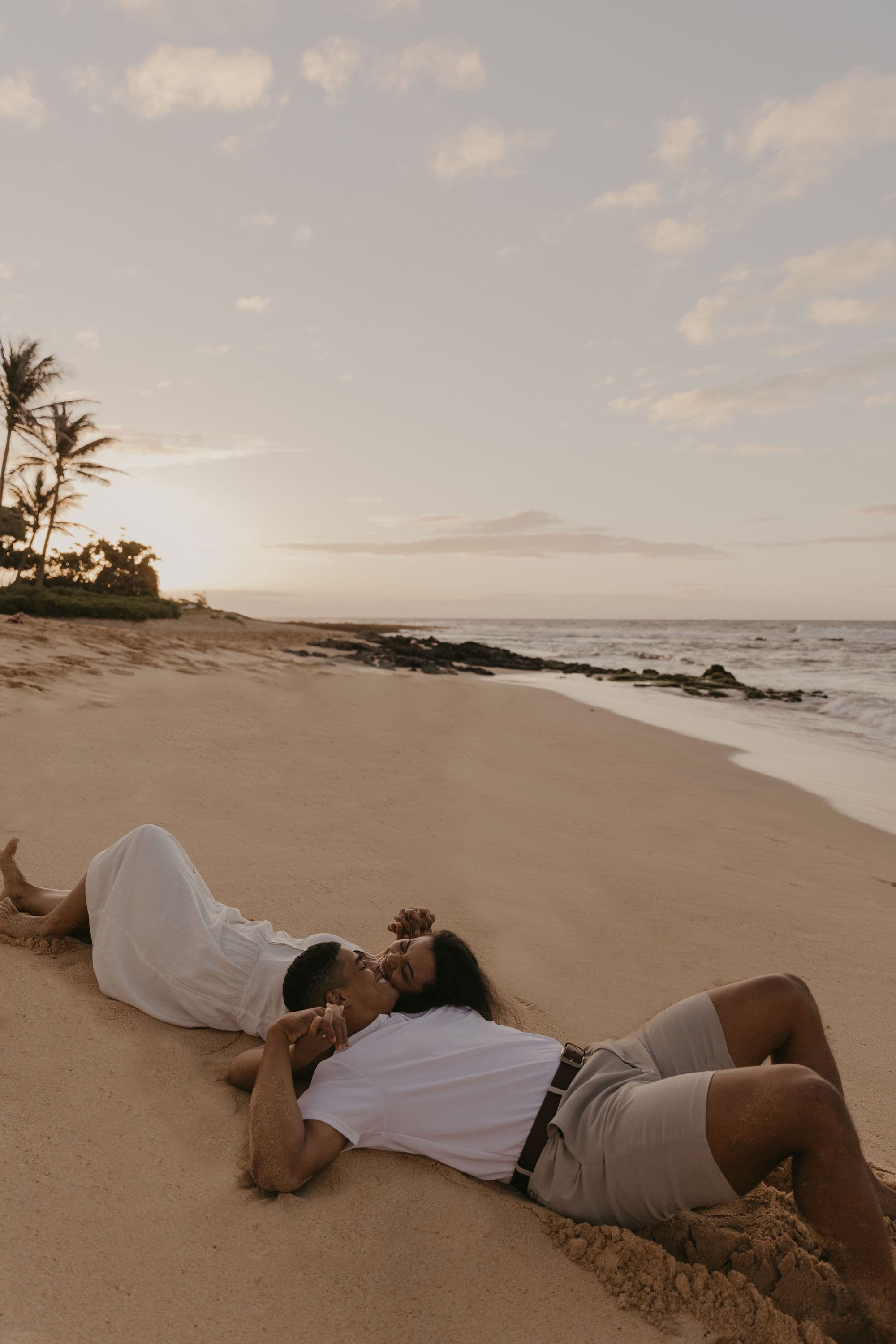 Couple kissing in the sand of a beach in Oahu, Hawaii