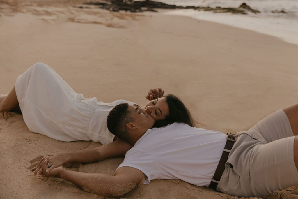 Couple kissing in the sand of a beach in Oahu, Hawaii