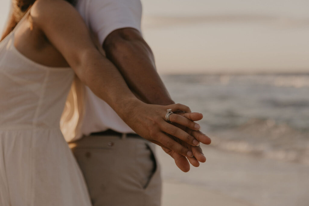 couple's hands on the beach at sunrise in Oahu, Hawaii