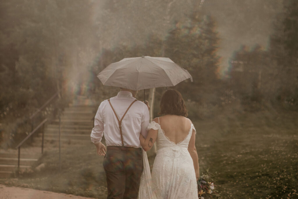 Bride and groom walking in the rain under an umbrella at their Crested Butte Elopement