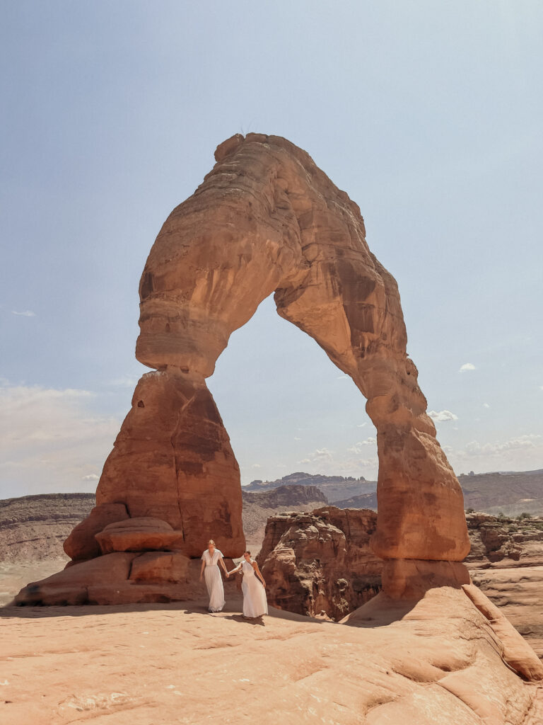 Brides walking under Delicate Arch at Arches National Park, Utah