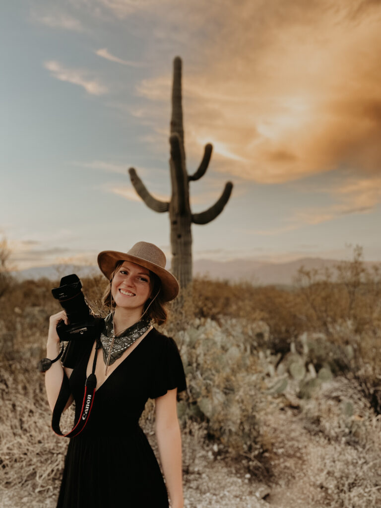 Photographer standing with camera in front of a saguaro cactus