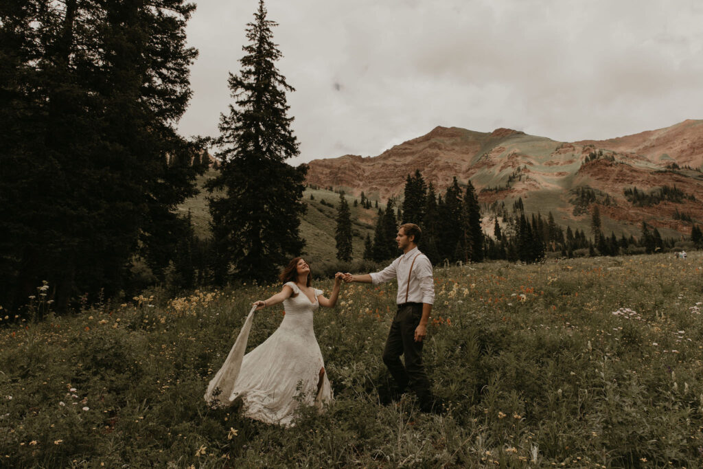 couple dancing in wildflowers at the base of a rocky mountain hike