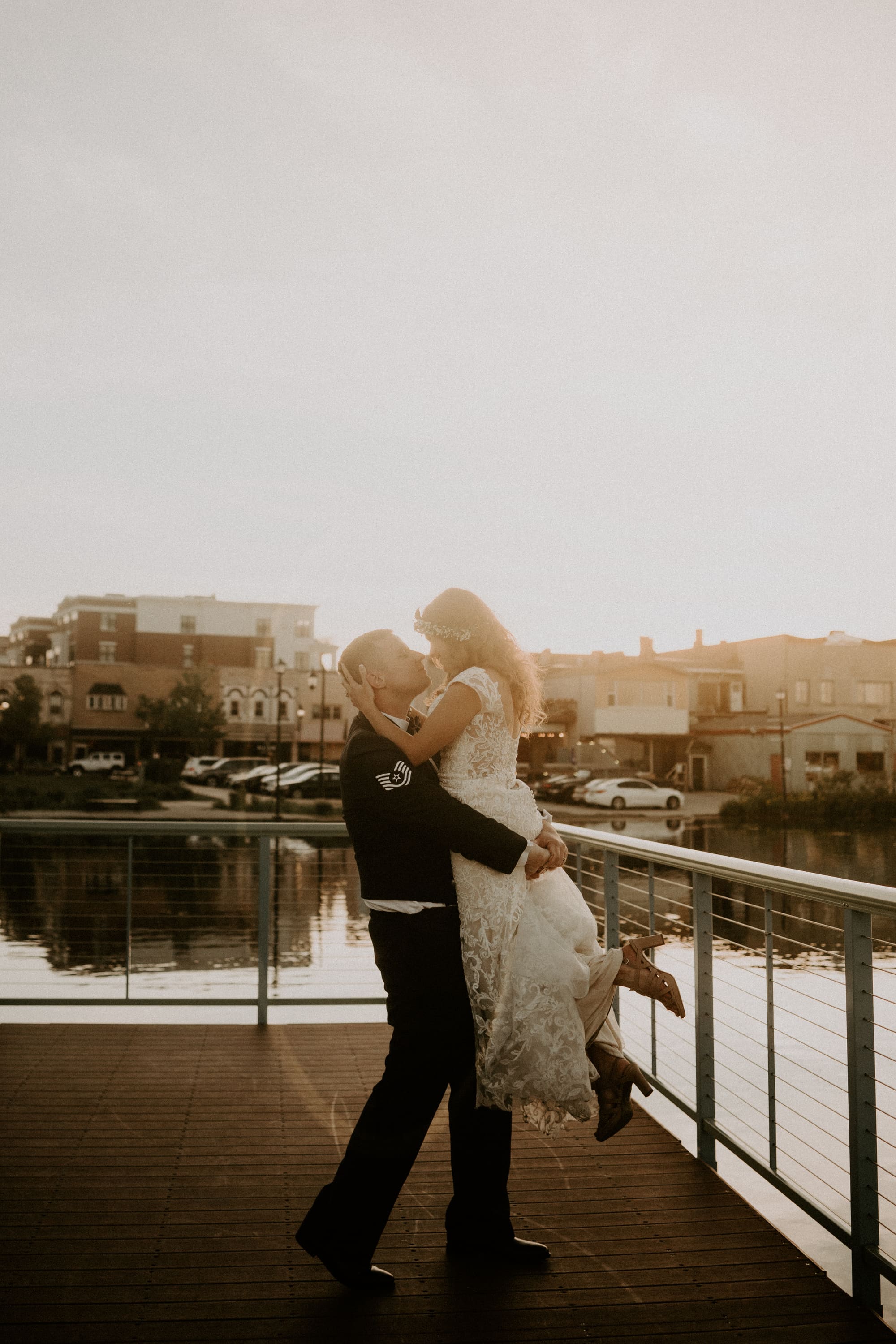 Wedding couple kissing on a pier with the sunset behind them