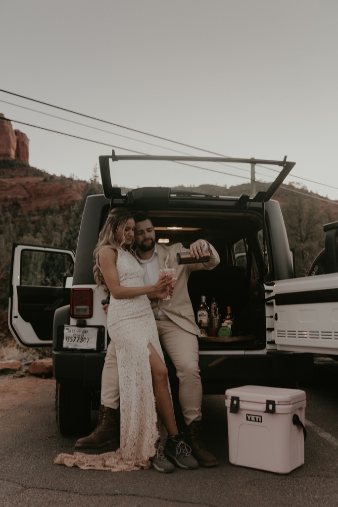 Couple making margaritas out of the back of a jeep after their elopement
