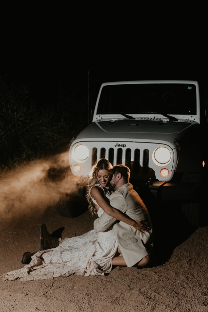 Couple dancing in dust in front of Jeep headlights