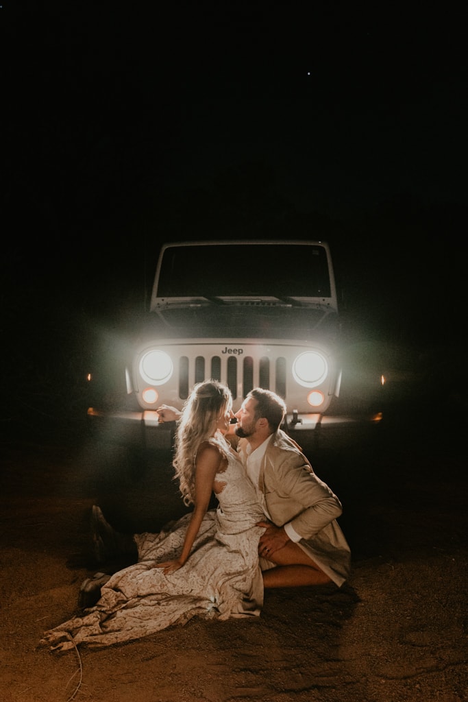 Couple kissing in front of Jeep headlights in the desert