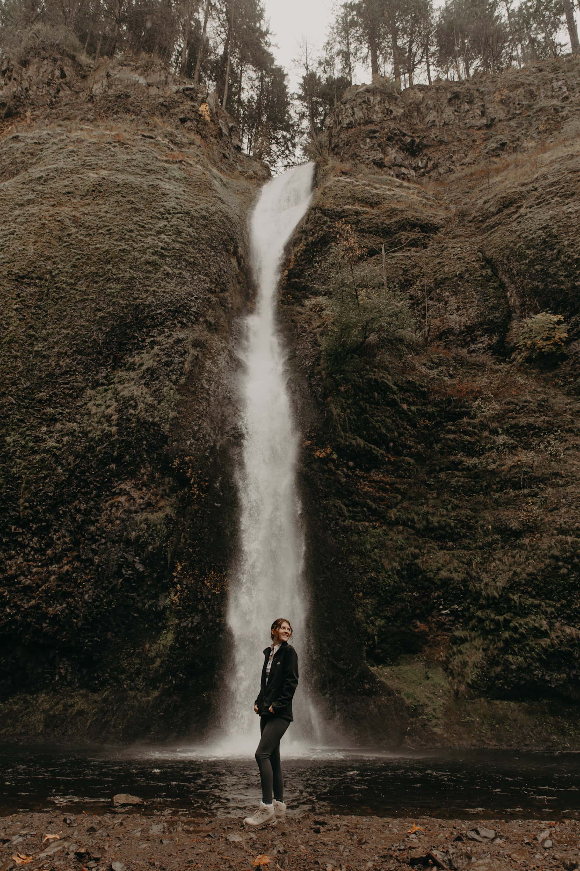 Girl standing in front of waterfall in the Pacific Northwest
