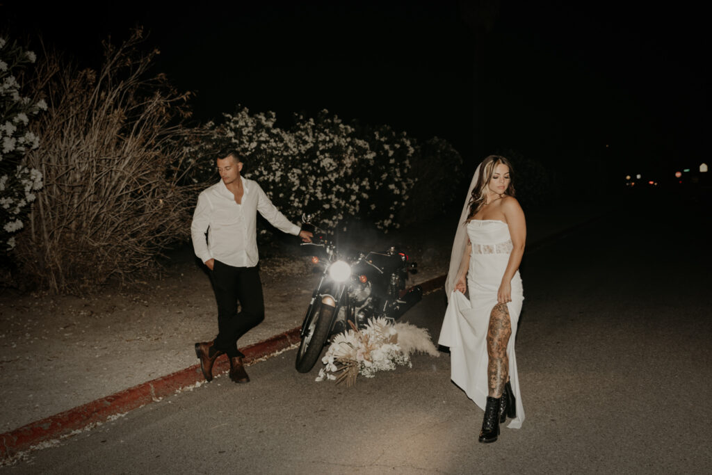 Night image of couple posing with their motorcycle in headlights